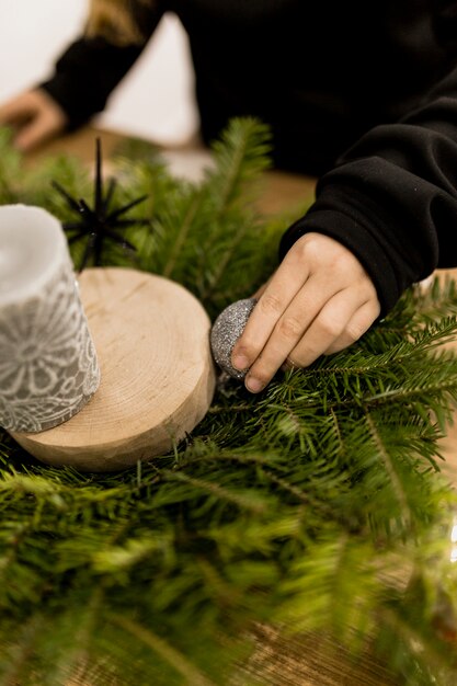 Crop person putting bauble on decoration