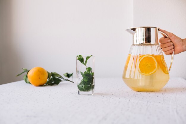 Crop person serving orange lemonade