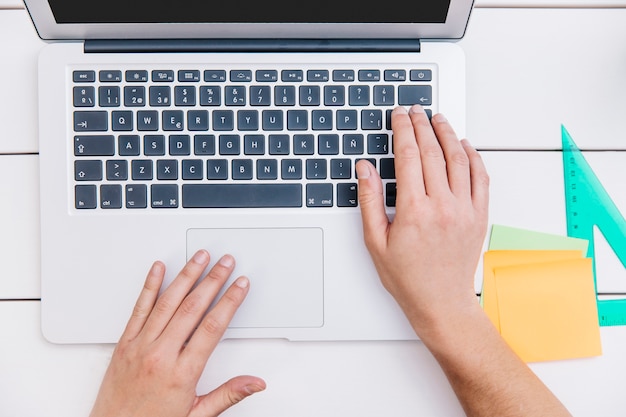 Crop person typing on laptop