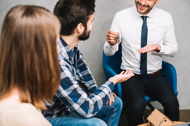 Foto gratuita ritaglia l'agente immobiliare fornendo le chiavi ai clienti