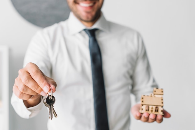 Crop real estate agent with keys and house