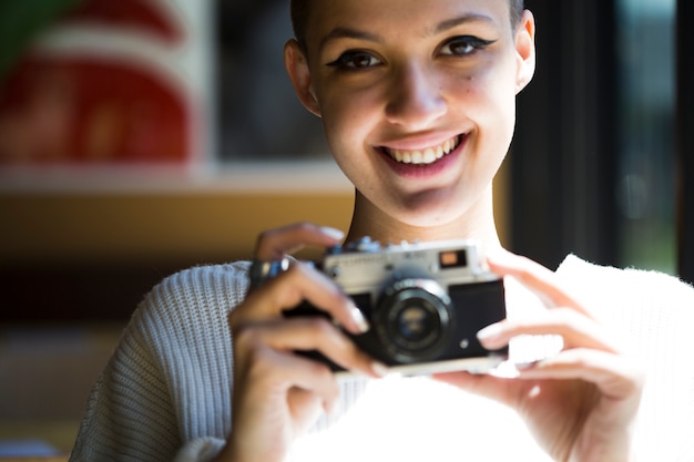 빈티지 카메라와 함께 웃는 여성 사진 작가 자르기