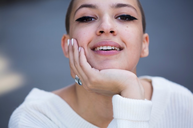 Foto gratuita raccolga il mento sorridente della tenuta della donna e l'esame della macchina fotografica