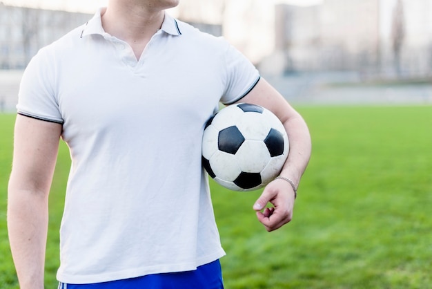 Crop sportsman carrying soccer ball