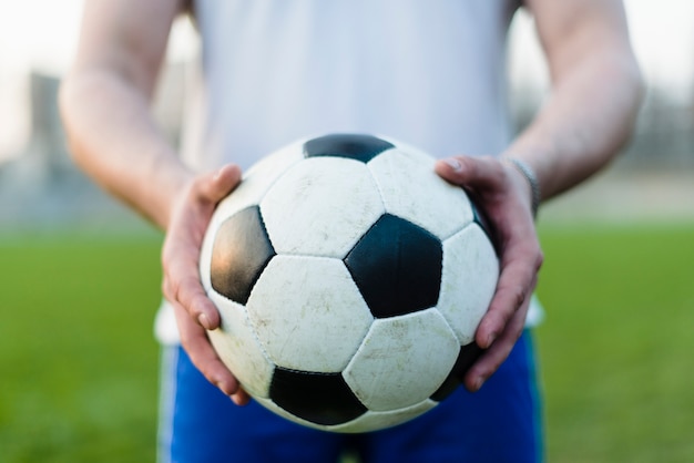 Crop sportsman showing soccer ball