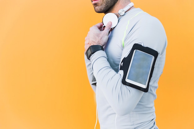 Crop sportsman with headphones and smartphone