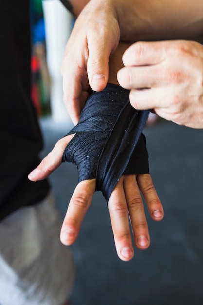 Crop sportsmen taping hand with elastic band