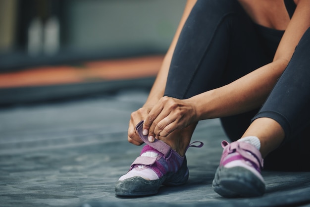 Crop sportswoman putting on trainers