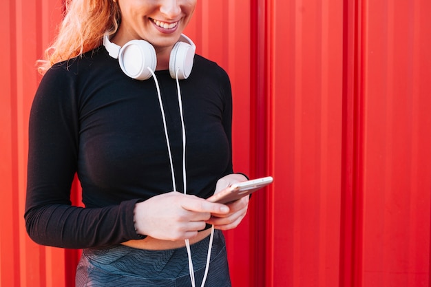 Crop sportswoman with smartphone