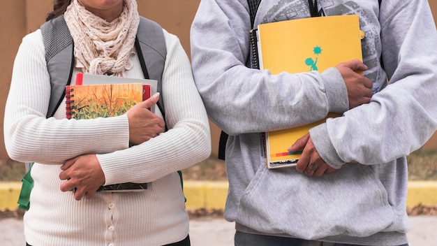 Crop students with notebooks and textbooks