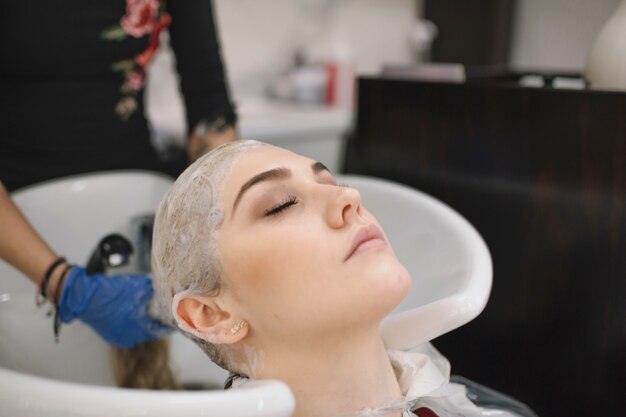 Crop stylist washing hair with shampoo