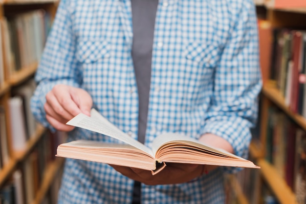 Crop teenager flipping pages of book