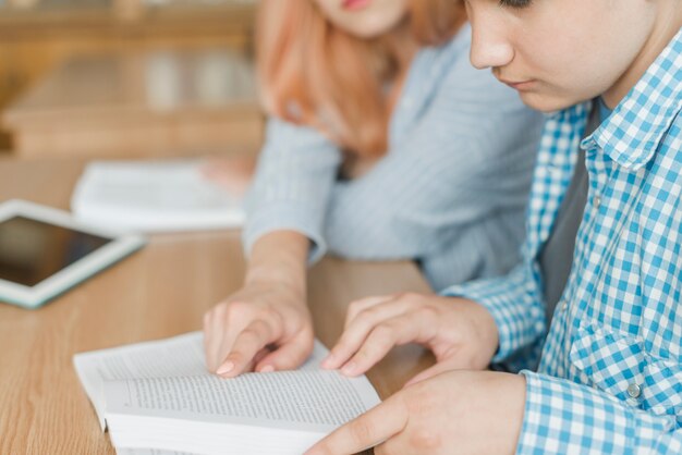 Crop teenager helping friend with studies