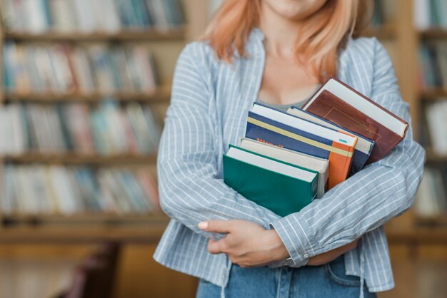 Crop teenager hugging books