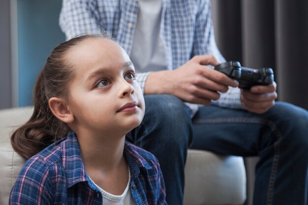 Crop teenager playing video game with sister