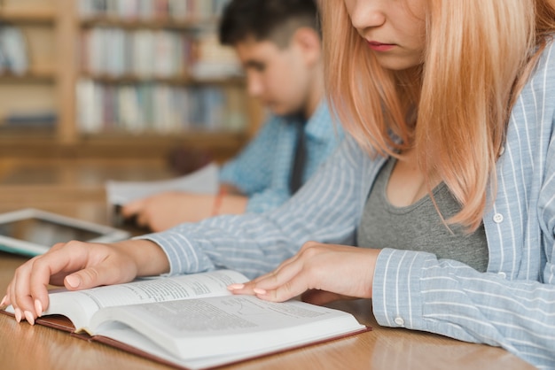 Crop teenager reading book