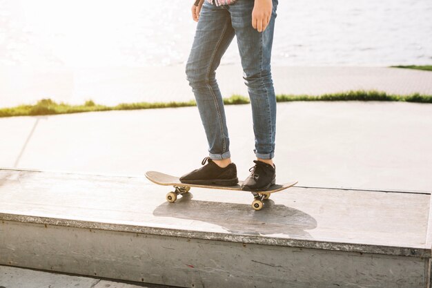 Crop teenager skateboarding on border