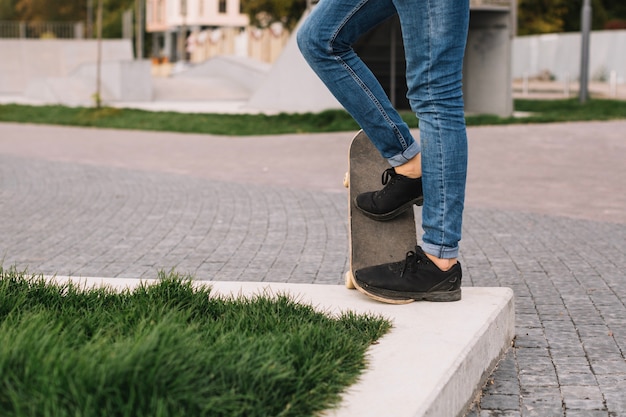 Crop teenager with skateboard standing on border