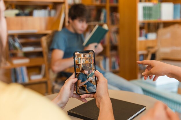 Подросток подросток делает фотографию друга в библиотеке
