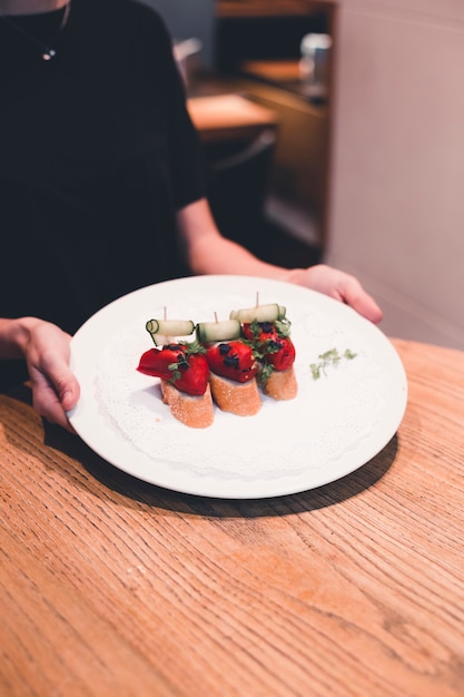 Crop waitress putting plate with tartines on table