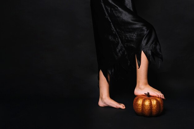 Crop witch stepping on pumpkin