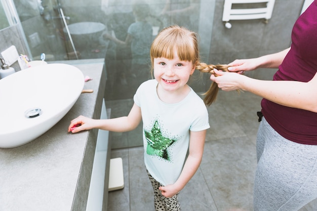 Foto gratuita raccolga la figlia sorridente dell'intrecciatura della donna