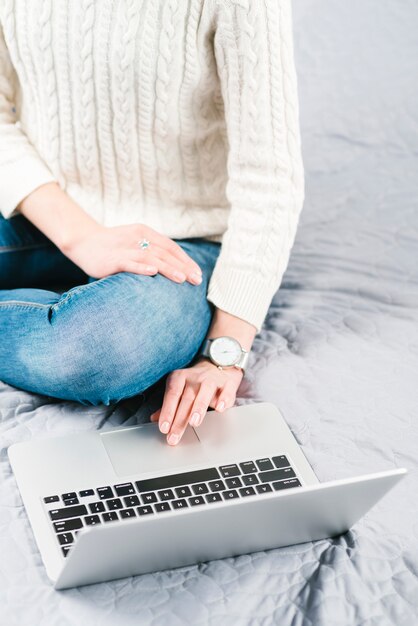 Crop woman browsing laptop on nice bed