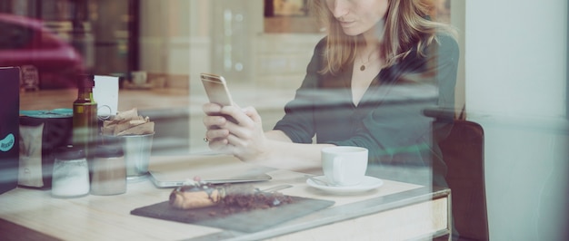 Foto gratuita donna che raccoglie smartphone navigando nel bel caffè