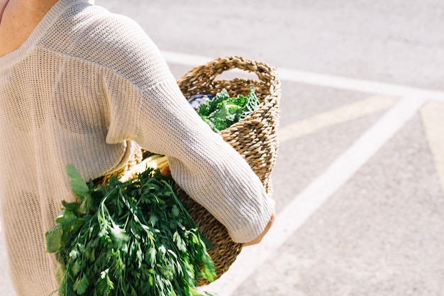 Free photo crop woman carrying basket with greenery