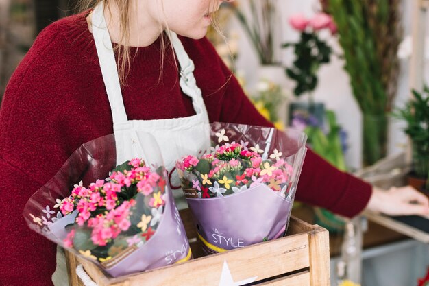 Crop woman carrying flowers for selling