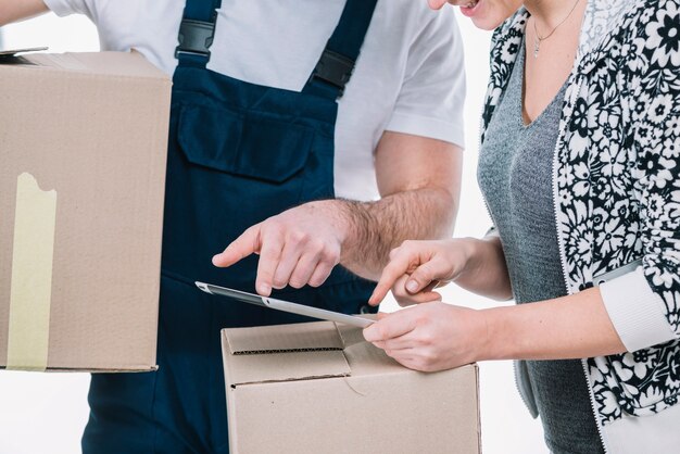 Crop woman and courier pointing at tablet