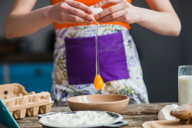 Crop woman cracking egg over bowl