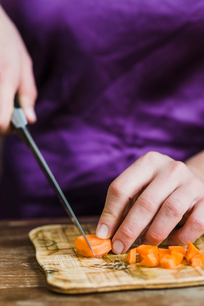 Crop woman cutting carrot