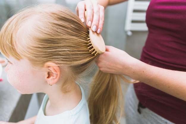 Free photo crop woman doing ponytail on daughter