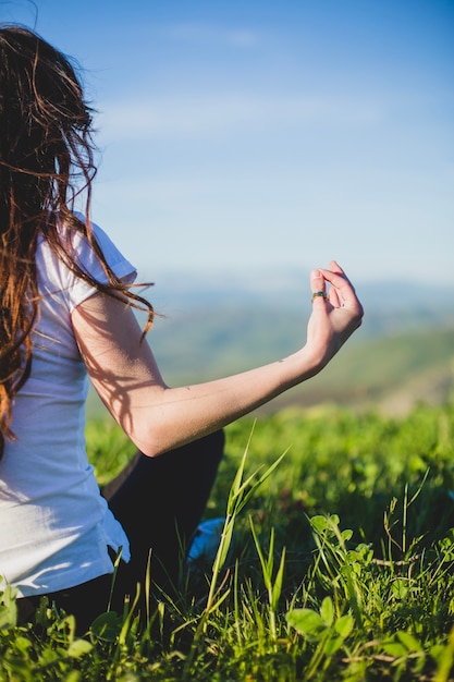 Crop woman doing yoga on field