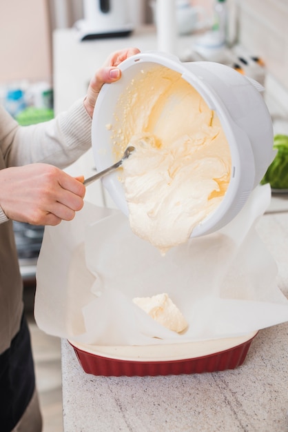 Crop woman filling baking pan with batter