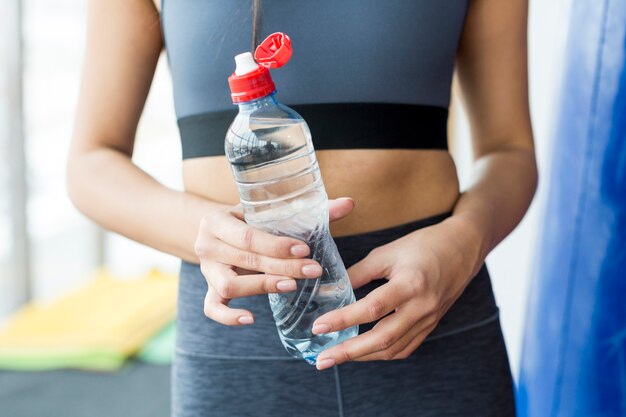 Crop woman in gym with water