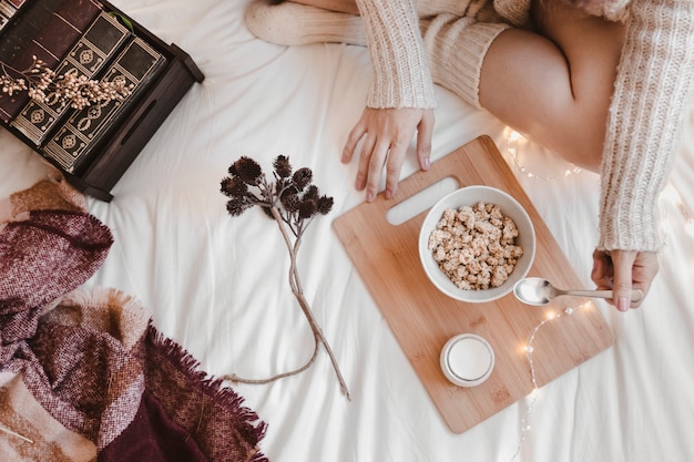 Crop woman having breakfast on bed