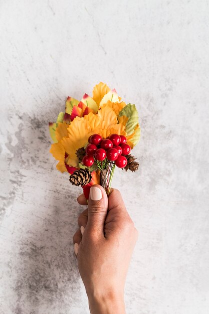 Crop woman holding autumn bouquet on shabby surface