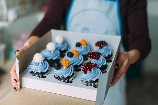 Free photo crop woman holding box with muffins