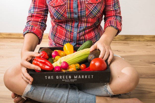 Crop woman holding pallet full of vegetables