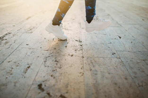 Crop woman jumping on pavement