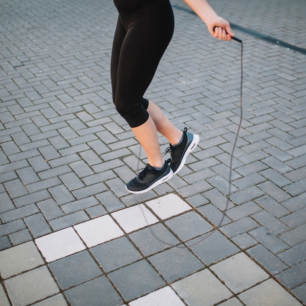 道路にロープでジャンプする作物の女性