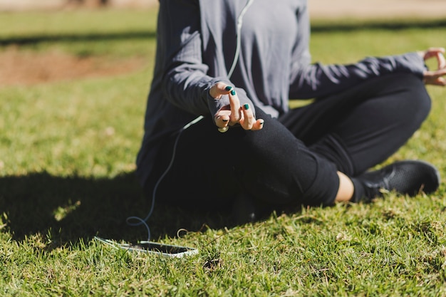 Crop woman listening to music and meditating