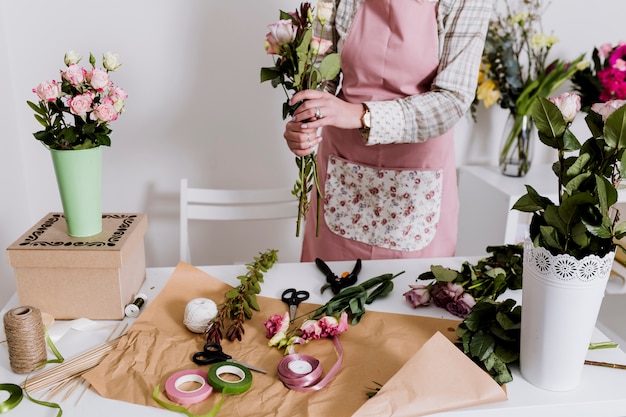 Crop woman making bunch of flowers