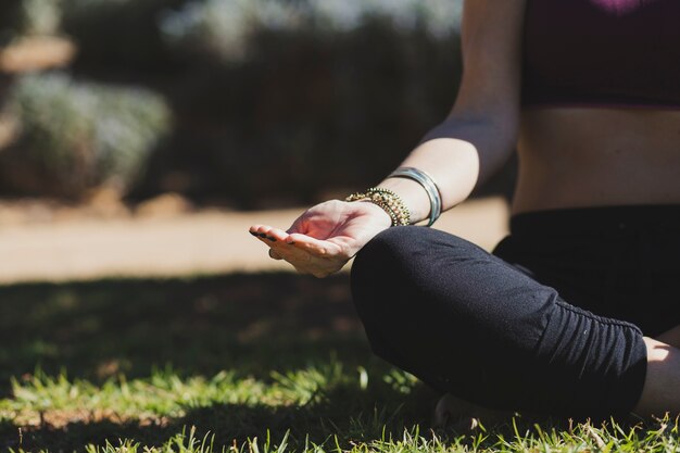 Crop woman meditating on sunny day