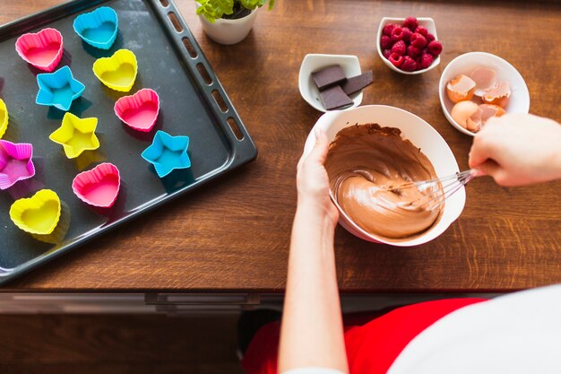 Crop woman mixing batter for cupcakes