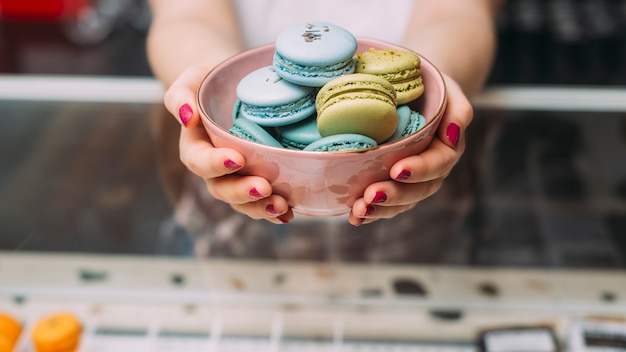 Free photo crop woman offering macaroons