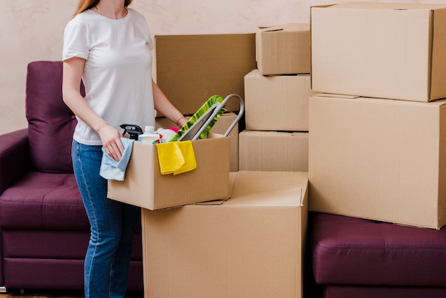 Crop woman packing things near sofa