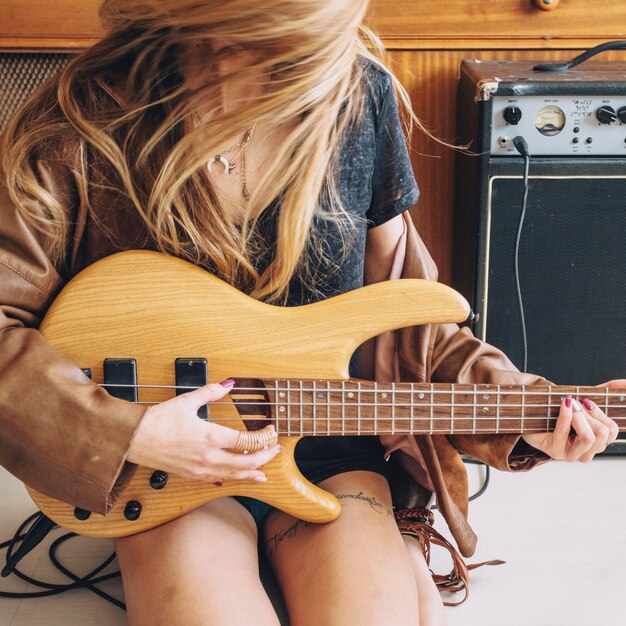 Crop woman playing guitar near cupboard